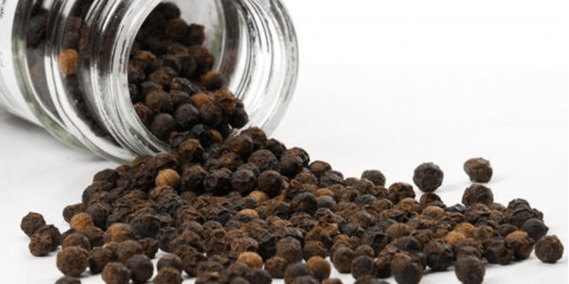 alt: Hạt tiêu đen nguyên hạt được bảo quản trong lọ thủy tinh
